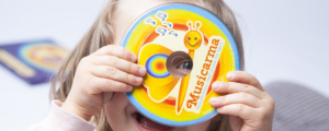 Et glad barn der smiler og kigger igennem Musicarma mindfulness cd'en.