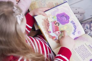Et barn der holder en bog med fantasifulde illustrationer og remser